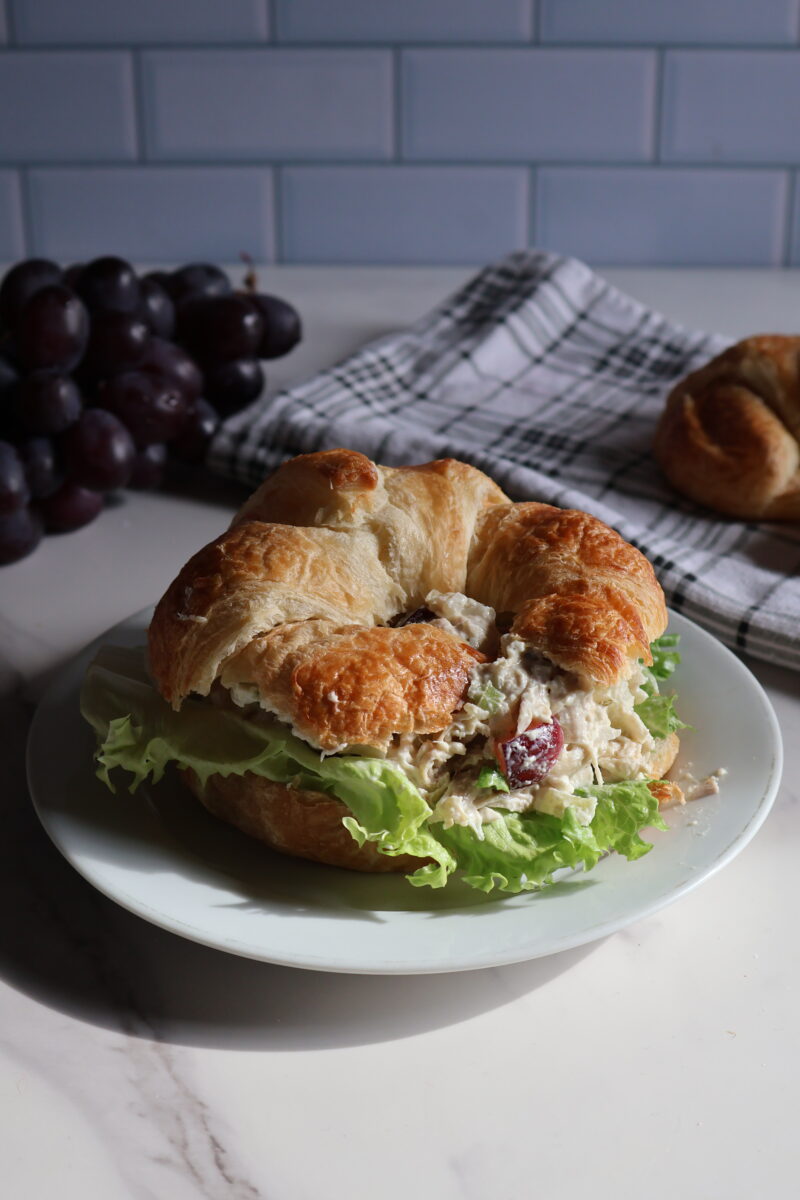 Chicken salad on croissant with grapes and lettuce.