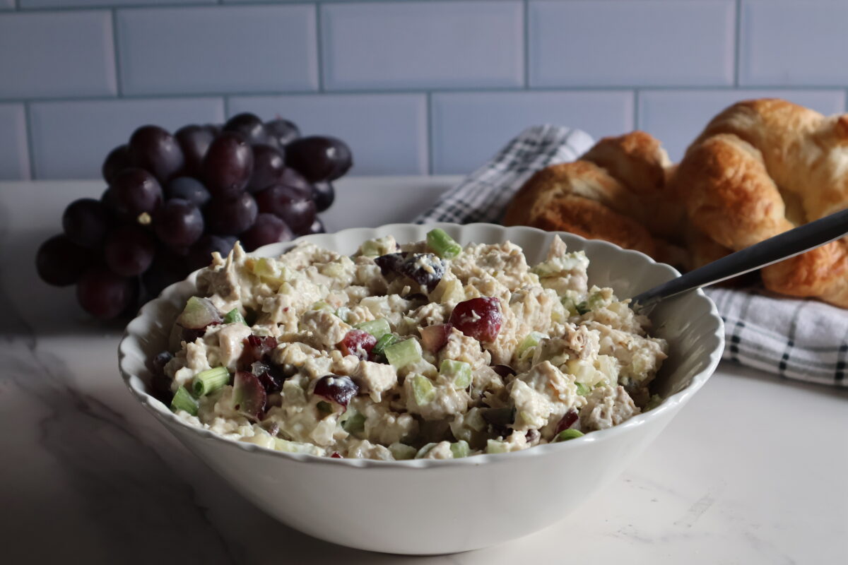 Chicken salad with grapes in a white bowl.