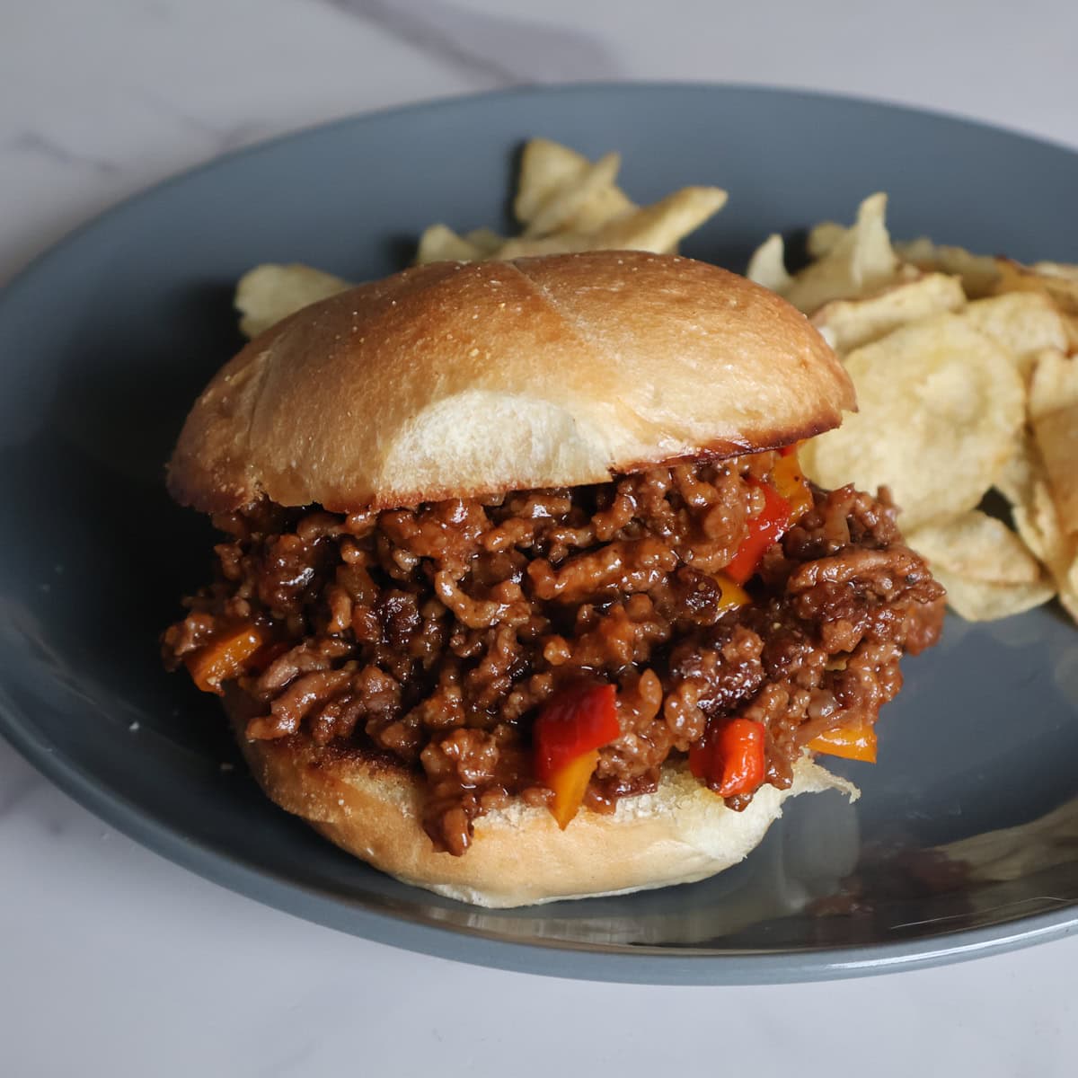 Sloppy joe on a toasted buttered roll with potato chips.