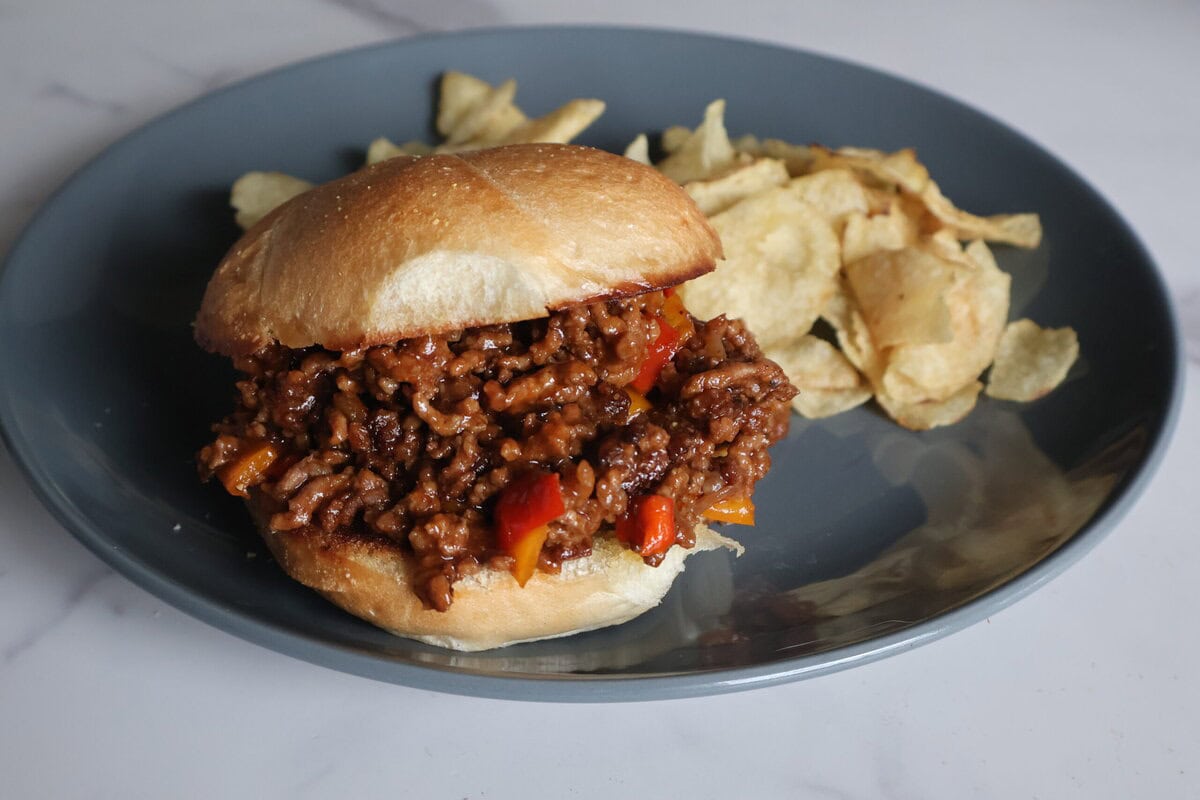 Sloppy Joe with potato chips on a gray plate.