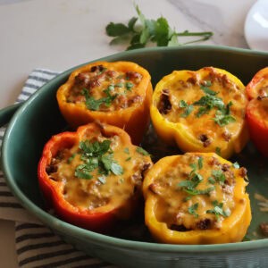 sloppy joe stuffed peppers in a green casserole dish
