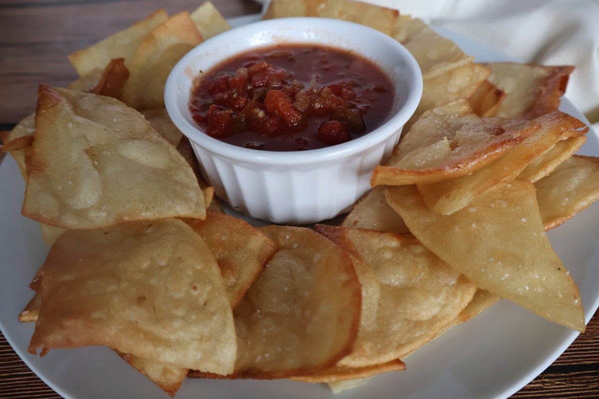 tortilla chips and salsa on a white plate with a napkin.