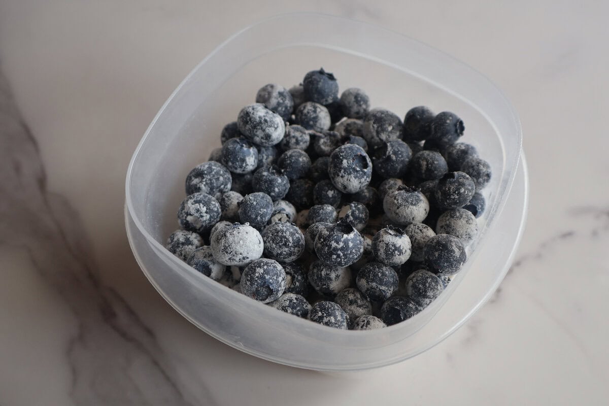 Blueberries mixed with flour in a clear container.