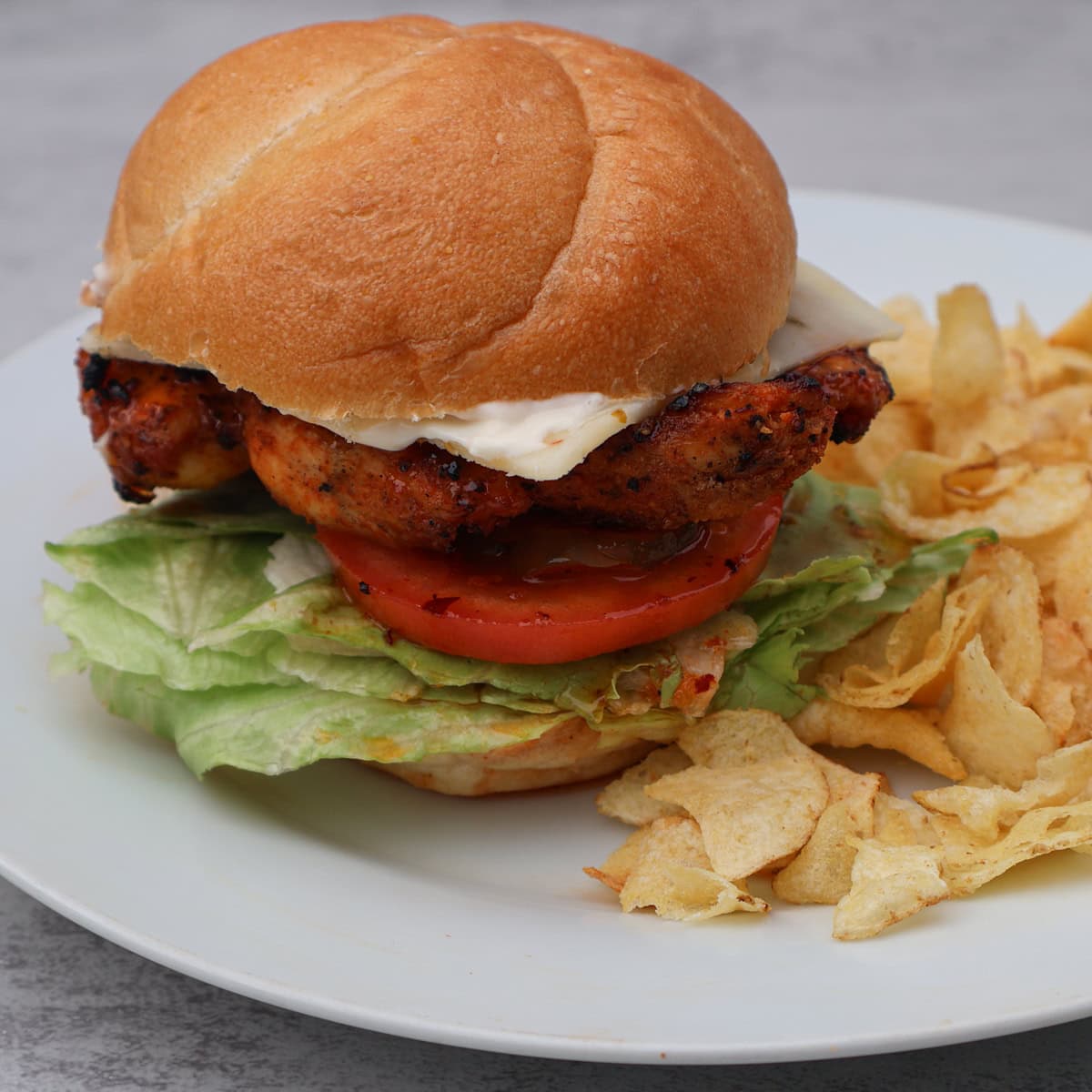 Hot honey chicken sandwich on plate with chips.