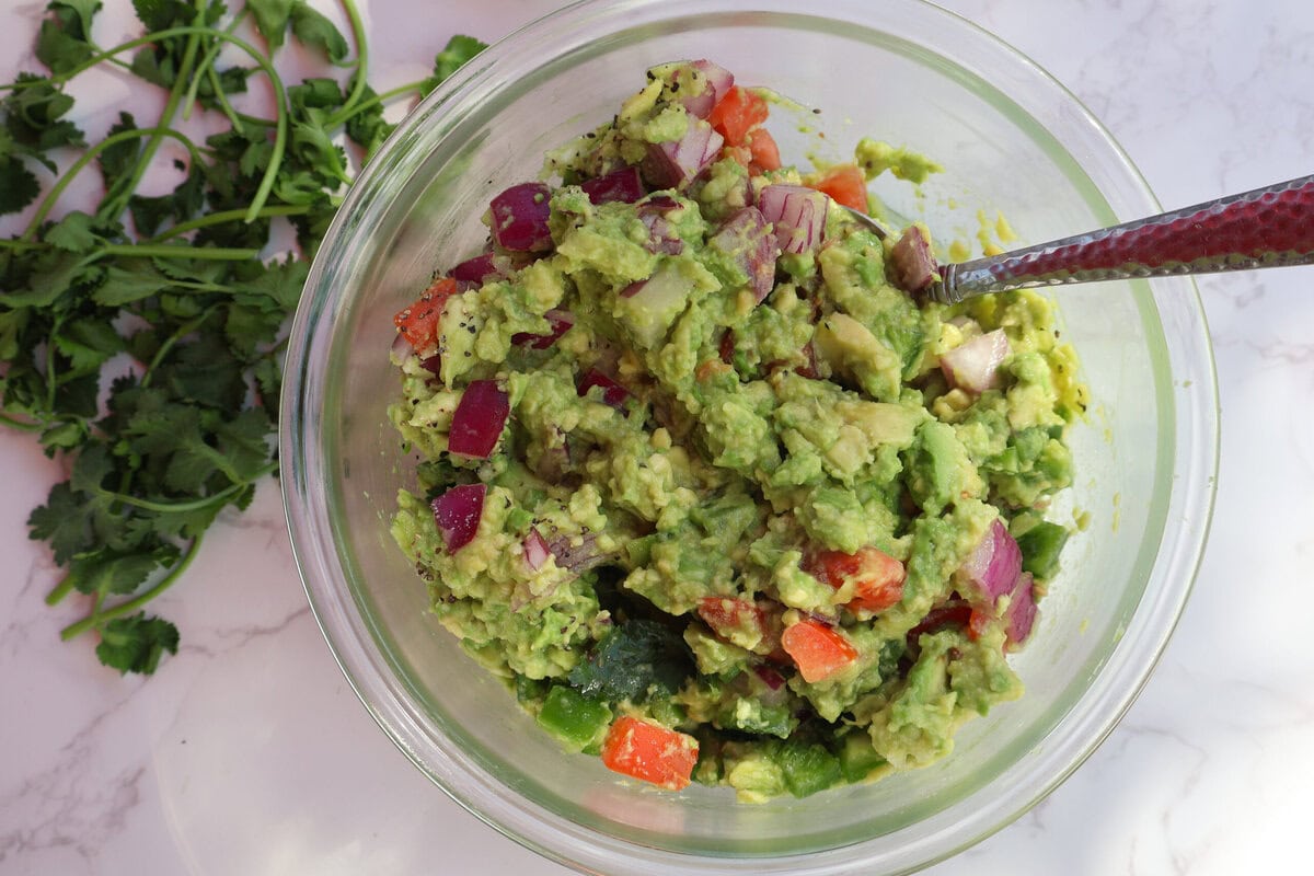 Guacamole in a glass bowl with cilantro.