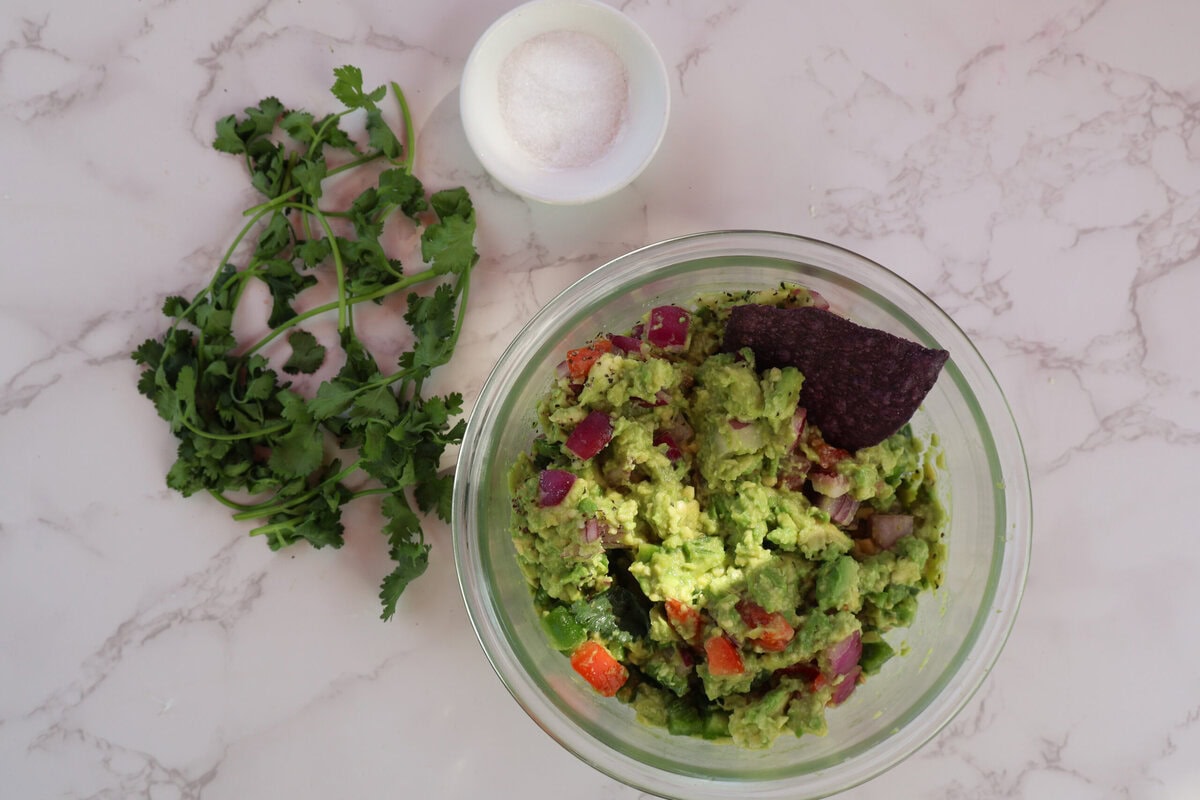 Guacamole in a glass dish with salt and cilantro.