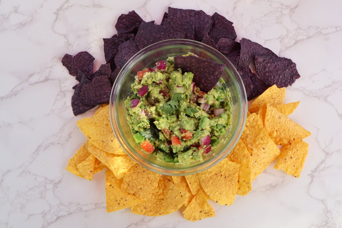 Guacamole in a glass bowl with tortilla chips.