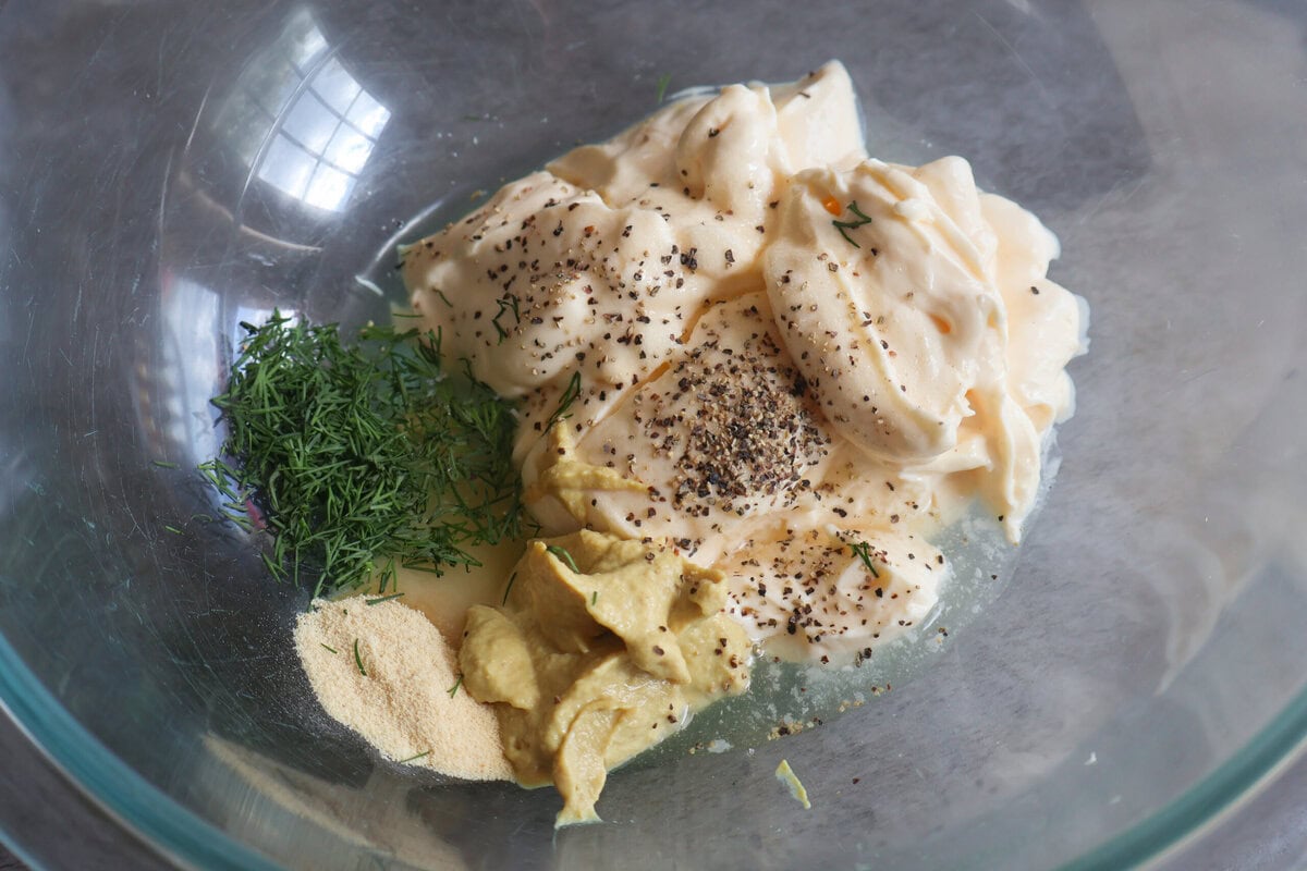 Mayo, mustard, spices, and herbs, in a glass bowl.
