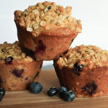 Blueberry banana oat muffins stacked with fresh blueberries.