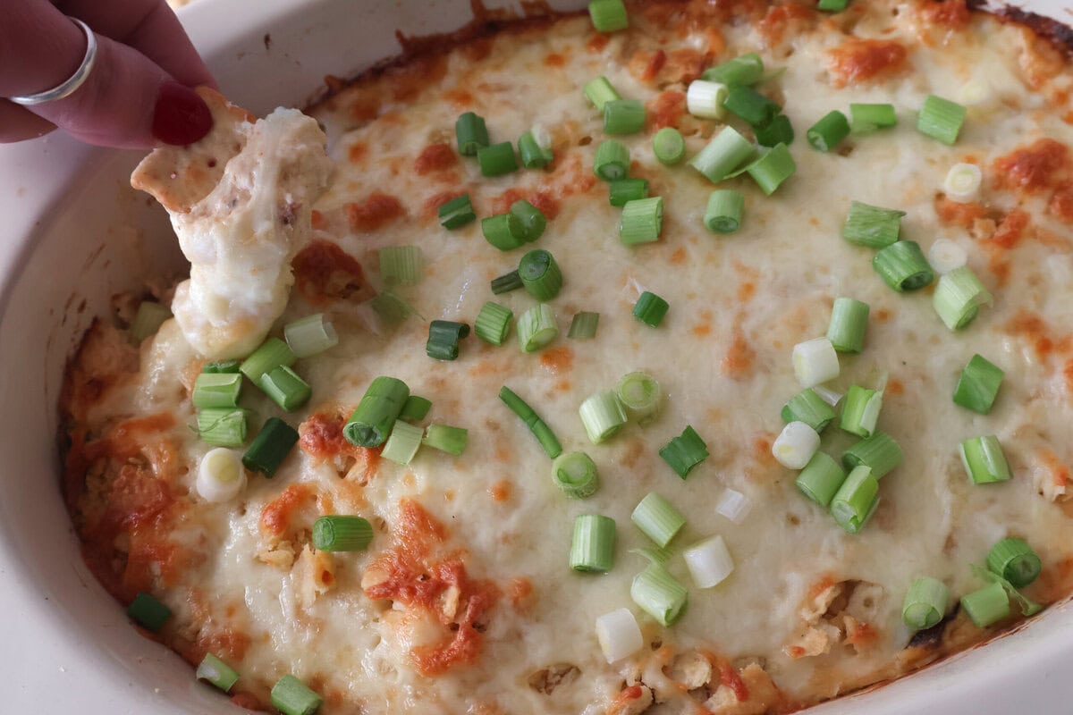 A cracker being dipped in the jalapeno chicken popper dip.