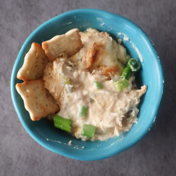 Small blue bowl of jalapeno chicken popper dip with crackers