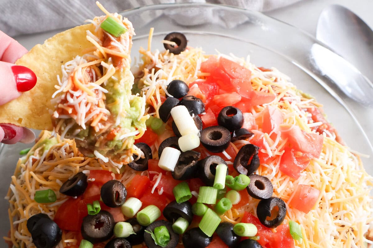 A tortilla chip dipped in the 5 layer dip.