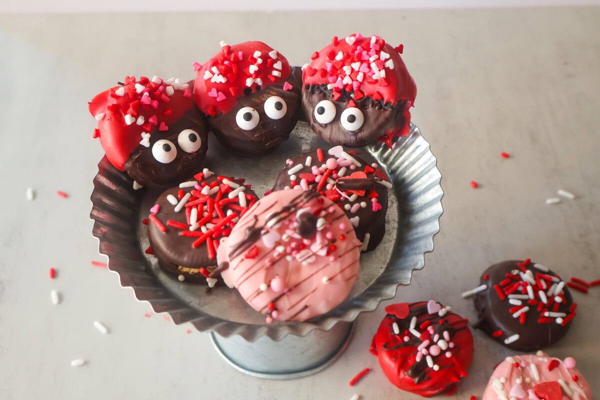 Chocolate covered oreos on a silver mini cake stand.