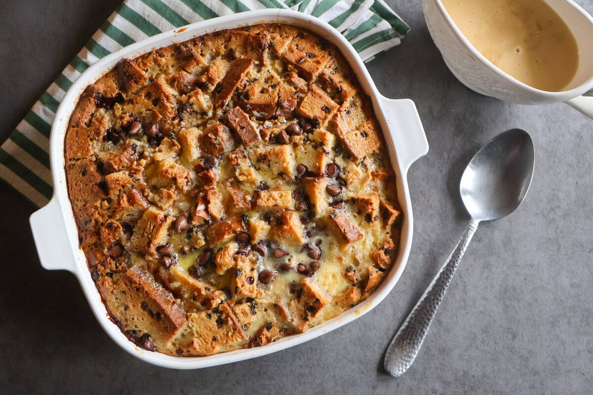 Irish Soda Bread Pudding with a spoon, green striped napkin and Vanilla Whisky Sauce.