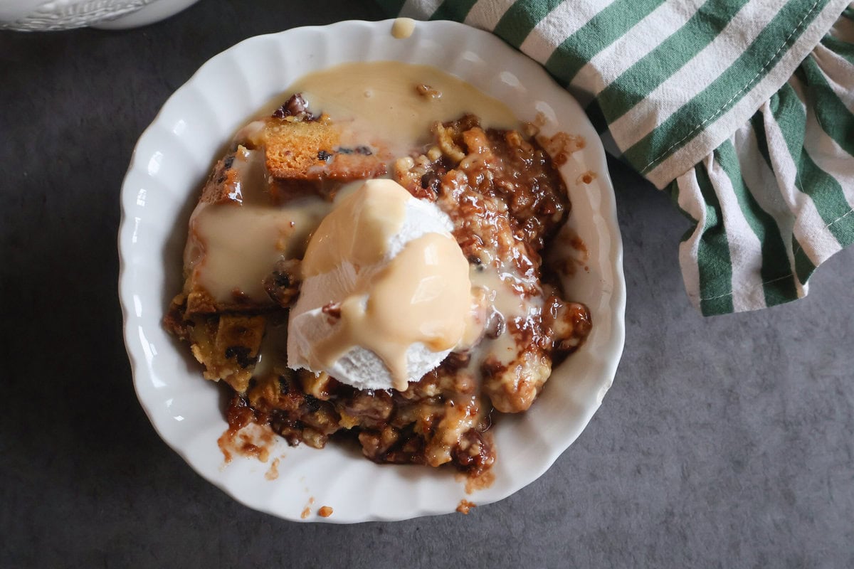Irish Soda Bread Pudding with Warm Vanilla Whisky Sauce in a white bowl with a green striped napkin.