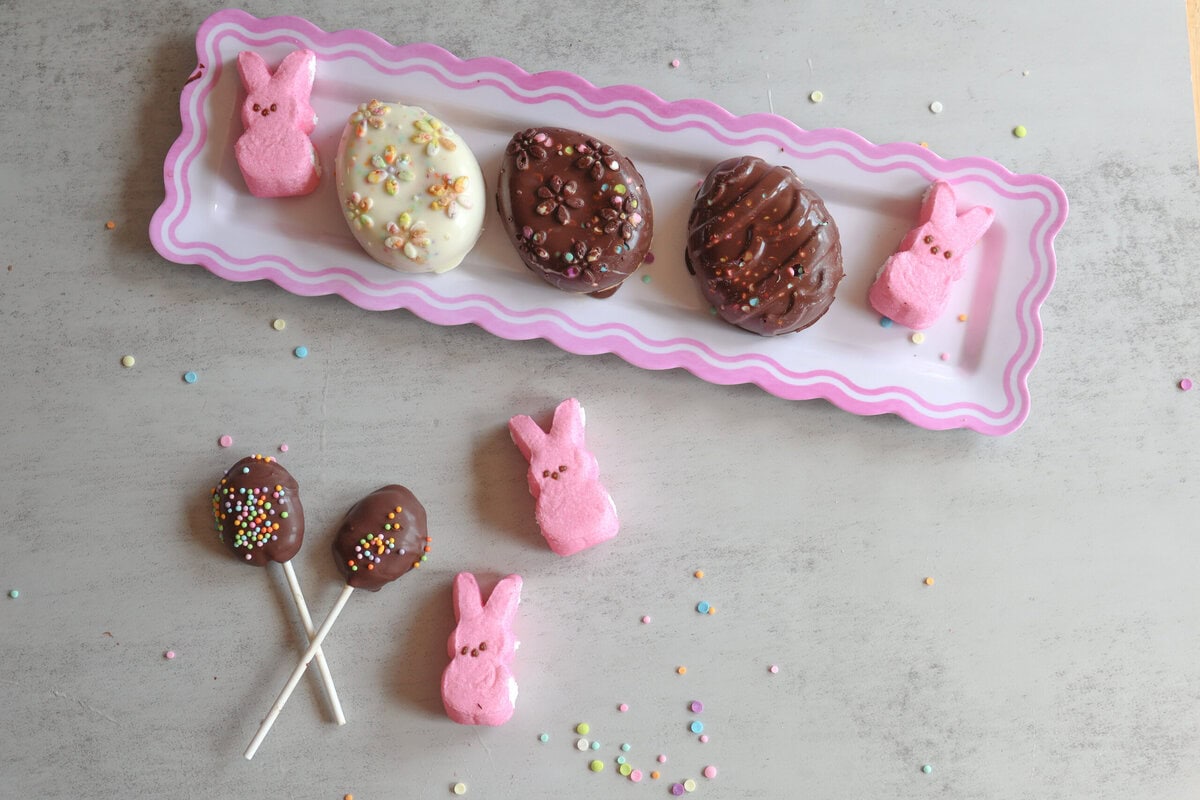 Peanut Butter Easter Eggs on a pink and white platter with bunny peeps and peanut butter pops.