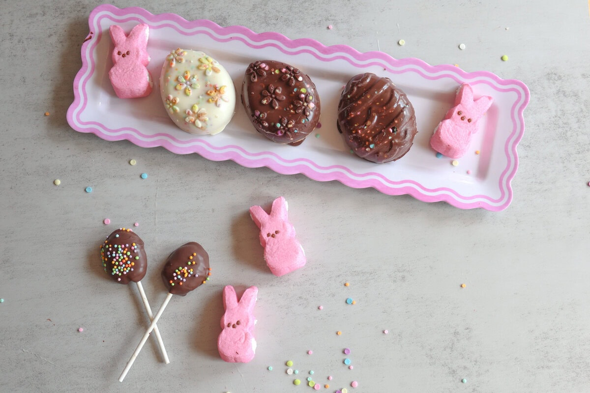 Peanut Butter Easter Eggs on a white platter with some peeps and lollypops.
