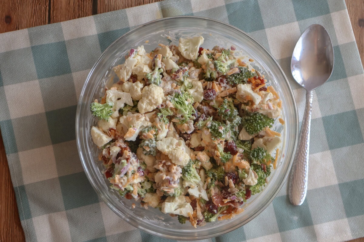 Creamy Cauliflower and Broccoli Salad in a glass dish with a spoon.