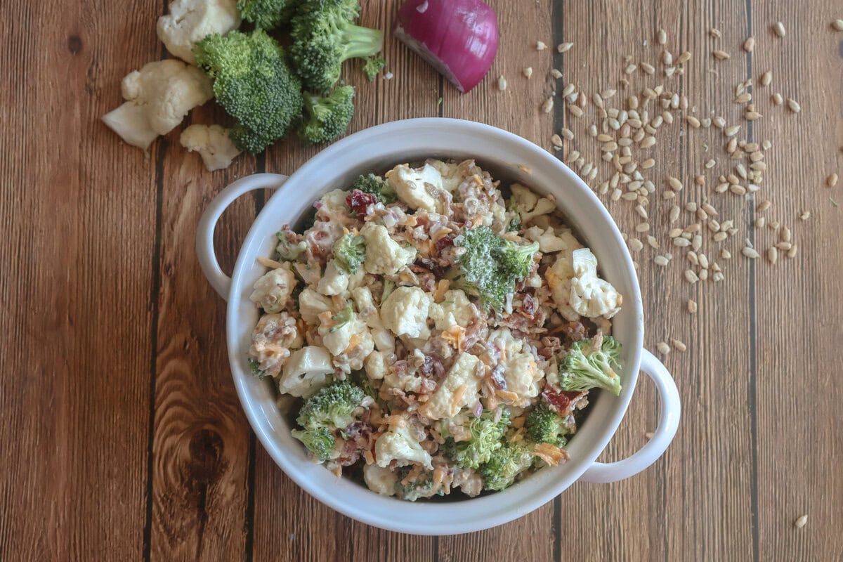 Creamy Cauliflower and Broccoli Salad in a white dishwith sunflower seeds.