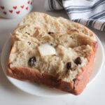 Sliced Spiced Hot Cross Buns Loaf with butter on a white plate.