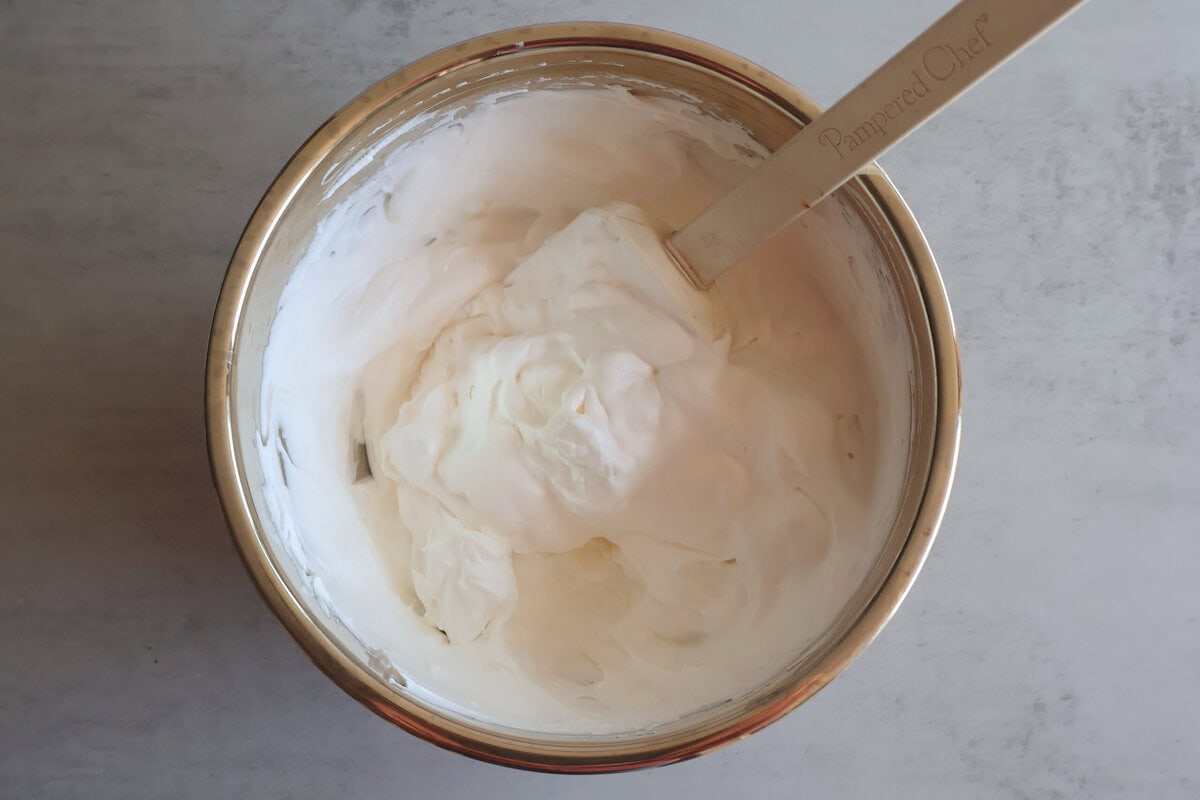 Cream cheese, powdered sugar, and whipped topping in a mixing bowl.