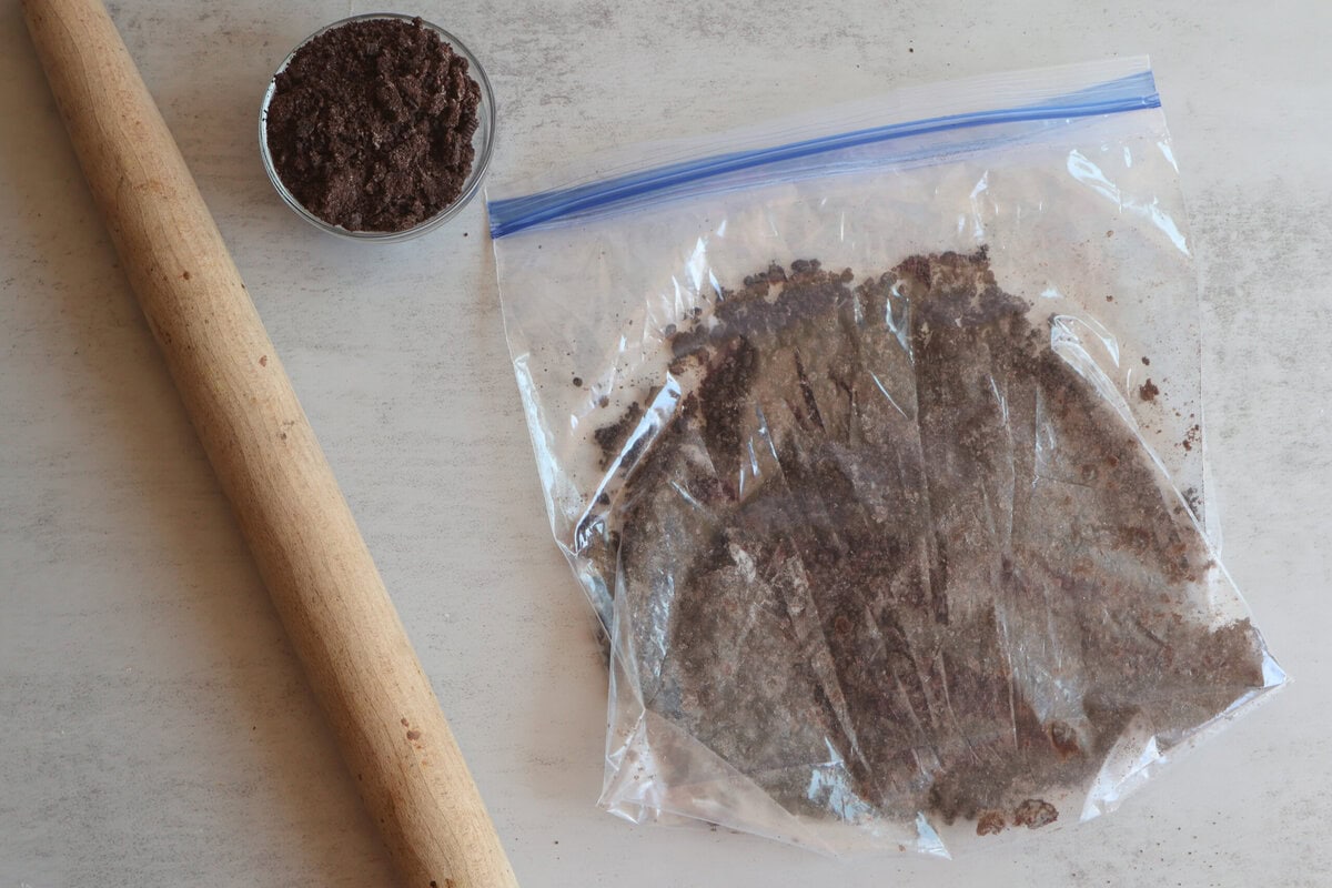 Crushed cookies in a zip lock bag with a rolling pin.