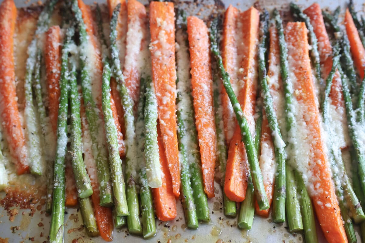 Asparagus and carrots on a baking sheet with Parmesan cheese.