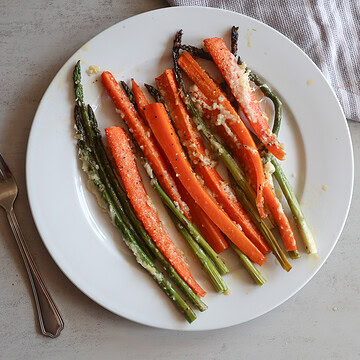 Honey garlic roasted asparagus and carrots on a white plate with a fork.