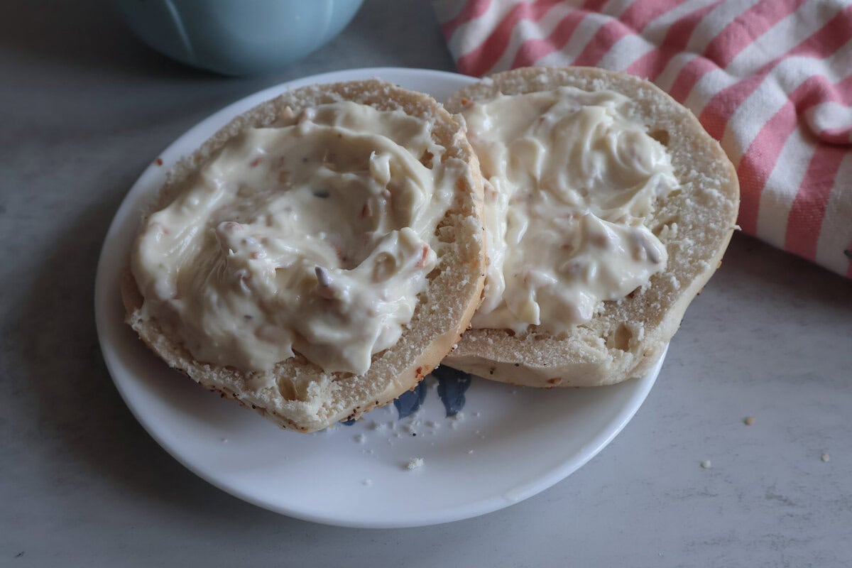Honey almond cream cheese on a bagel on a white plate.