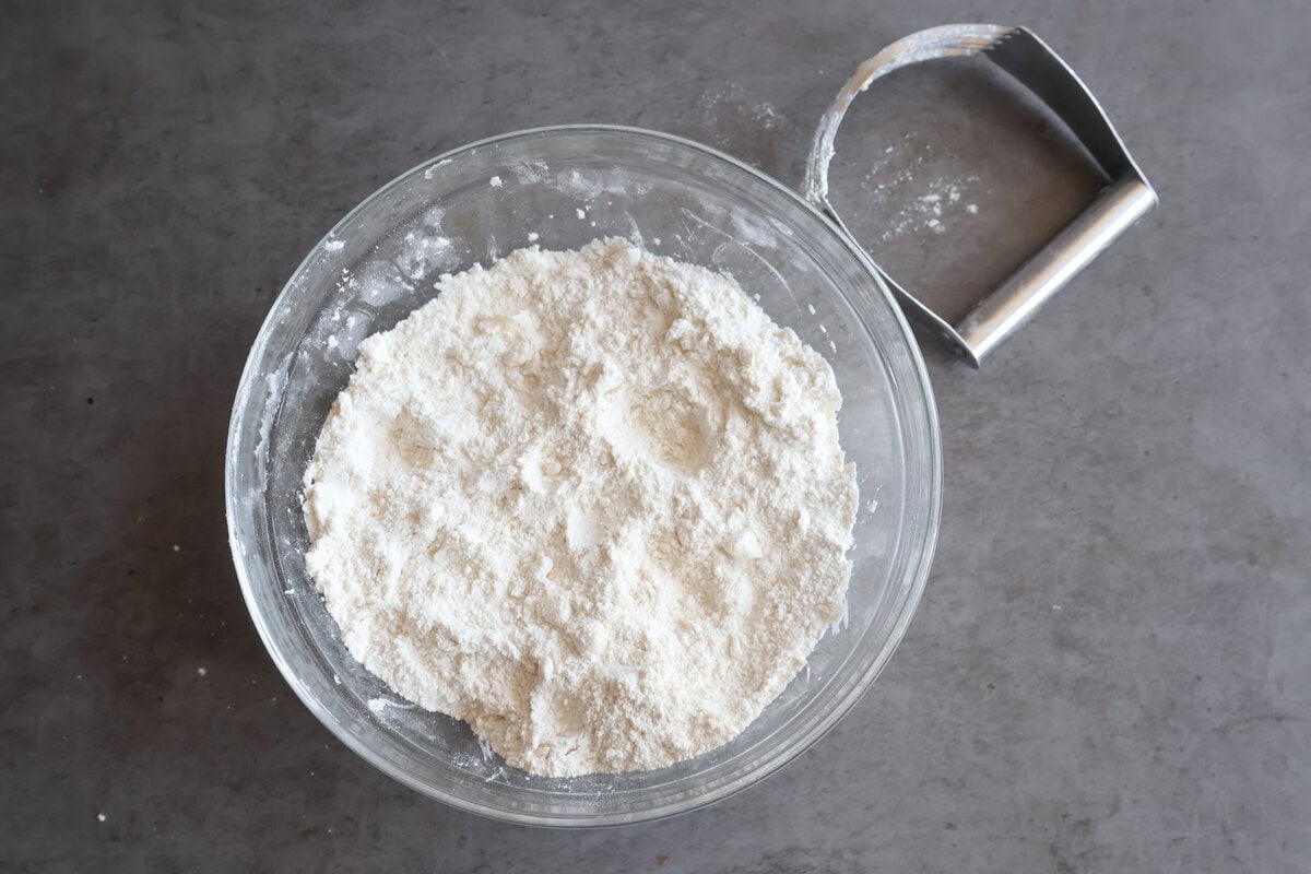 Flour mixture with butter in a glass bowl with a pastry cutter.