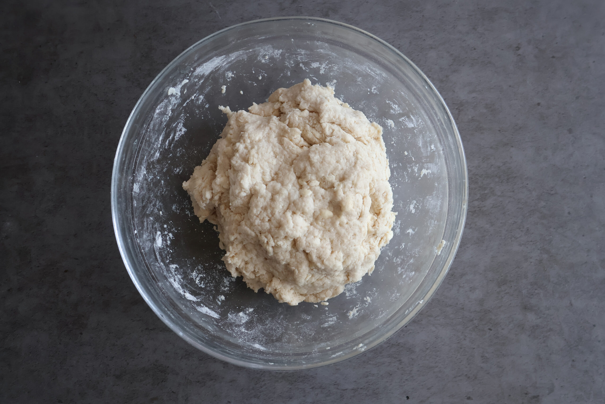 dough in a glass bowl with wet and dry ingredients.