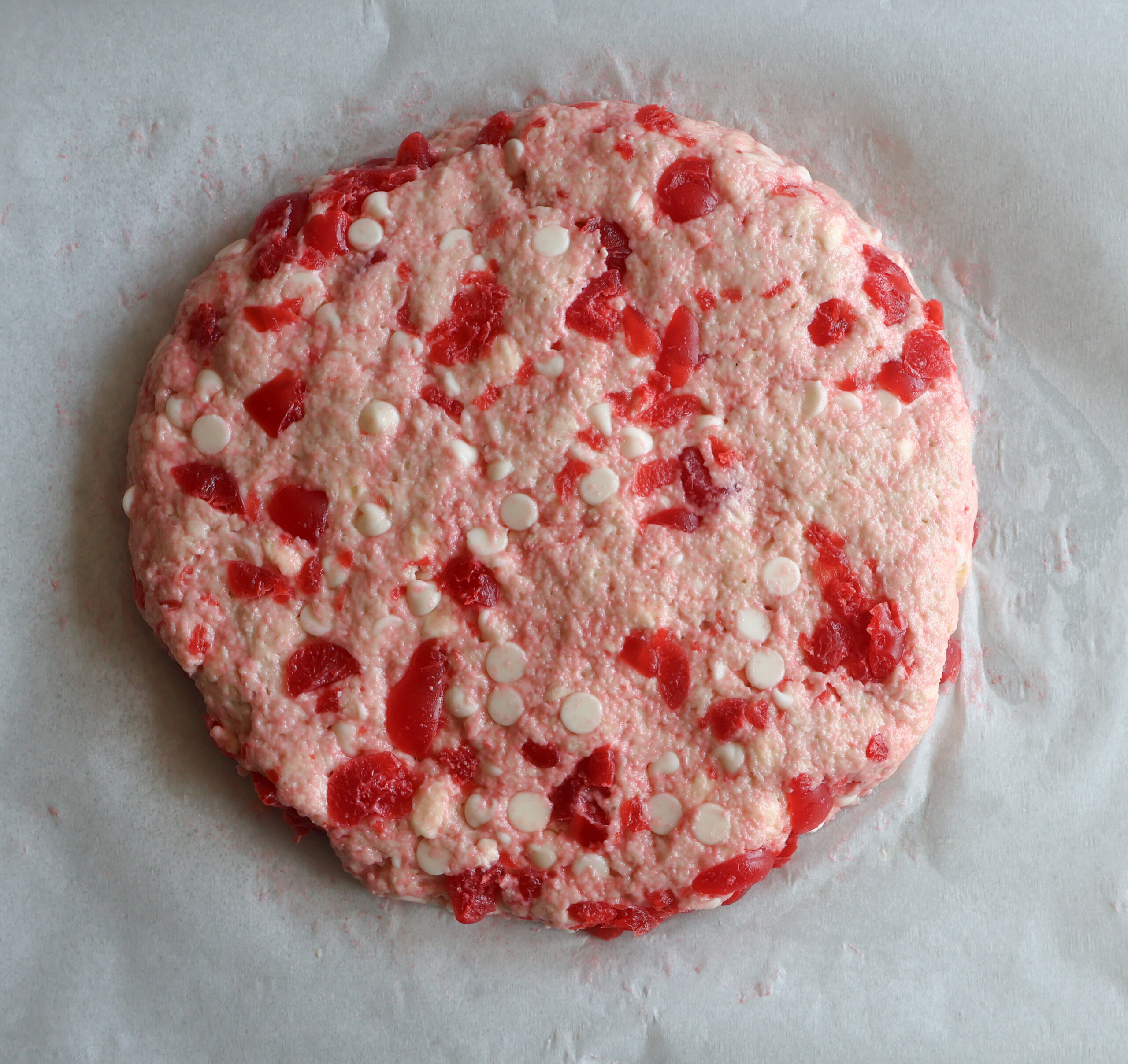 Scone dough on a sheet of parchment paper in a 9 inch round.