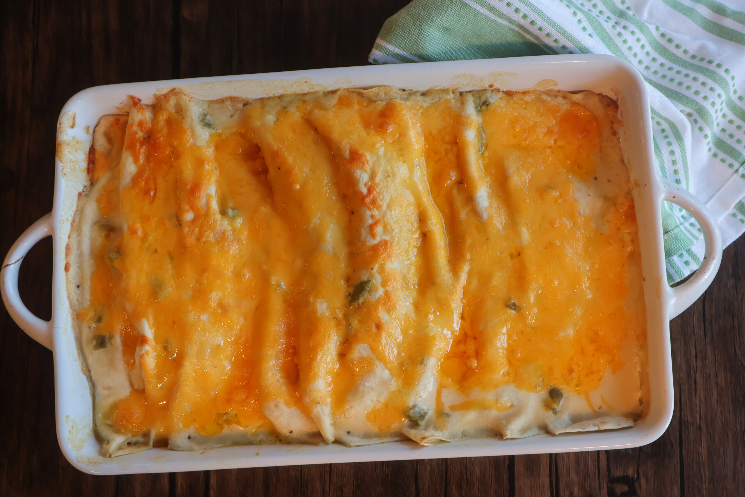 Baked Creamy chicken enchiladas in a white casserole dish.