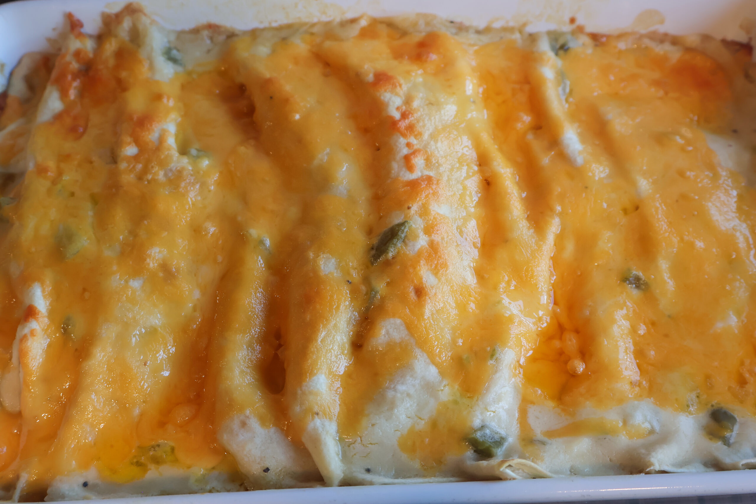 Creamy chicken enchiladas with melted cheese on top.