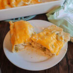 Creamy chicken enchiladas with sour cream sauce on a white plate.