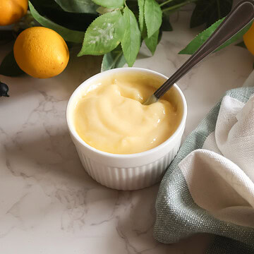 lemon curd in a white dish with a spoon.