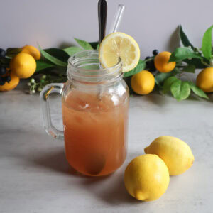 Summertime cooler in a mason jar glass with fresh lemons.