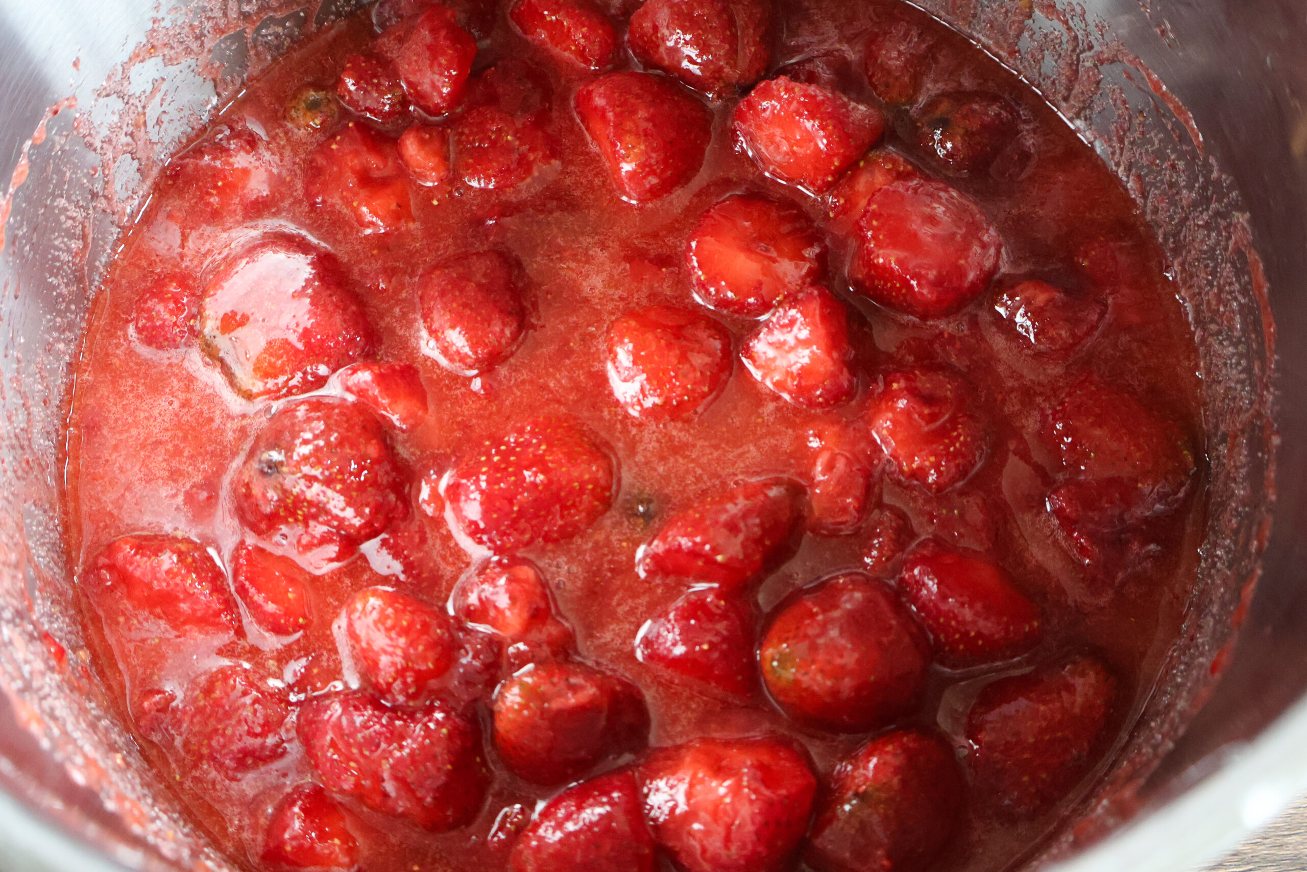 Honet strawberry preserves simmering in a pot.