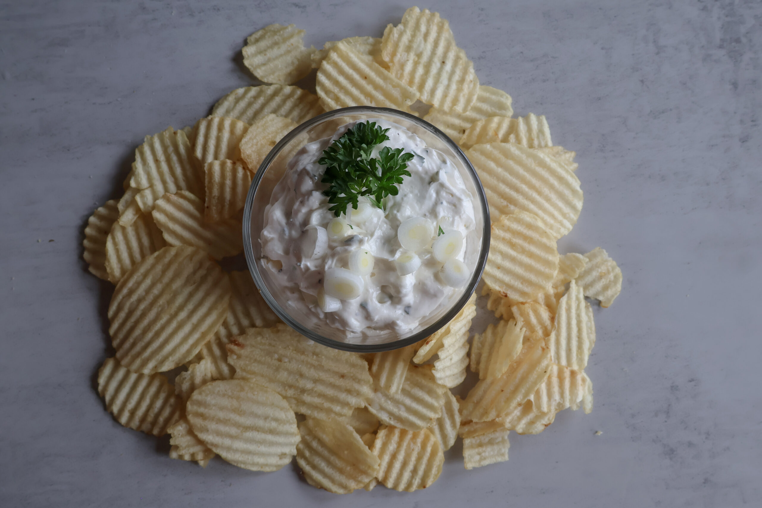 Creamy green onion dip in a small glass dish with chips.