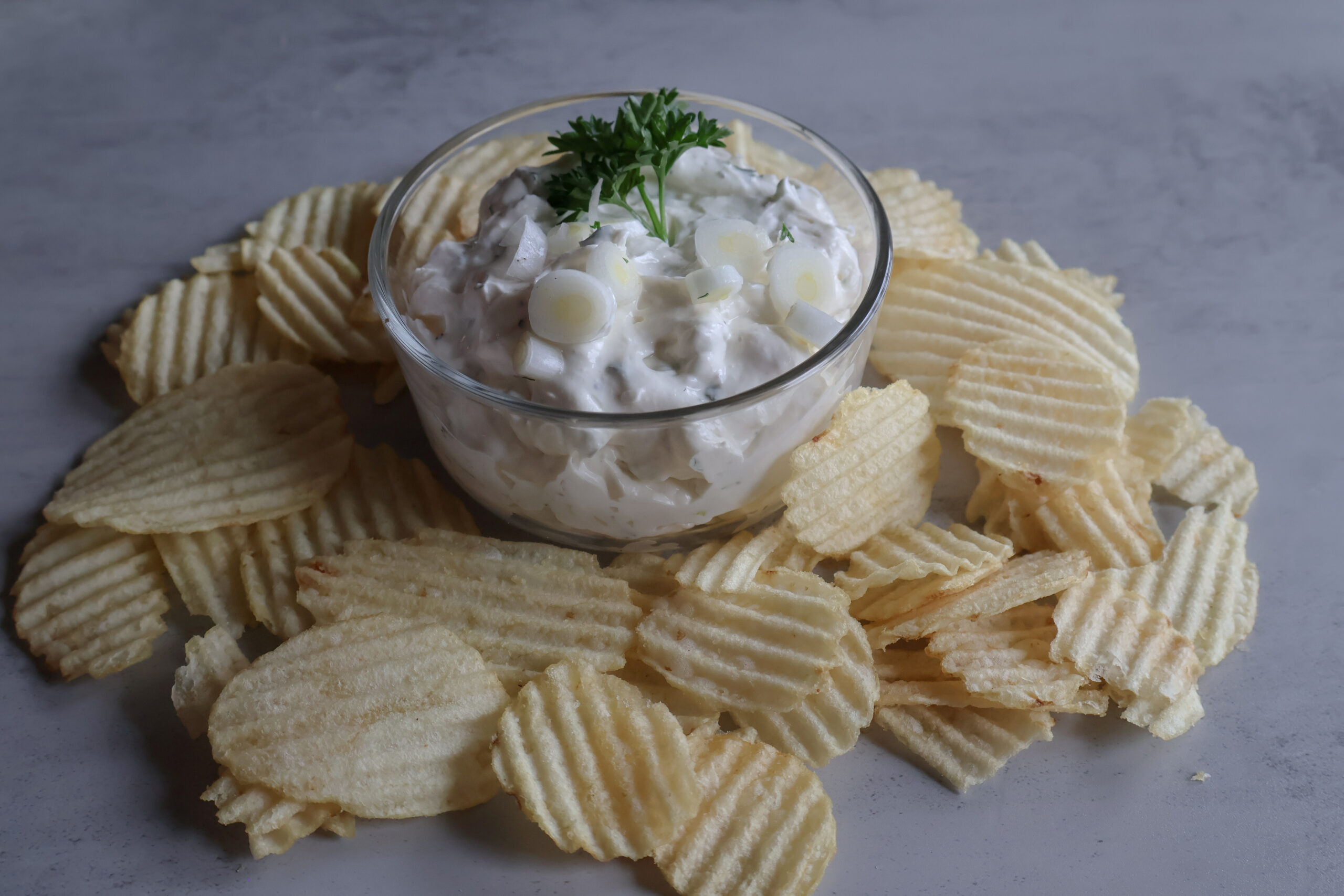 Creamy Green Onion Dip in a glass bowl with chips.