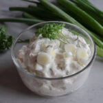 Creamy green onion dip in a glass bowl with fresh scallions.