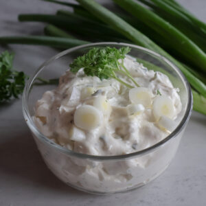 Creamy green onion dip in a glass bowl with fresh scallions.