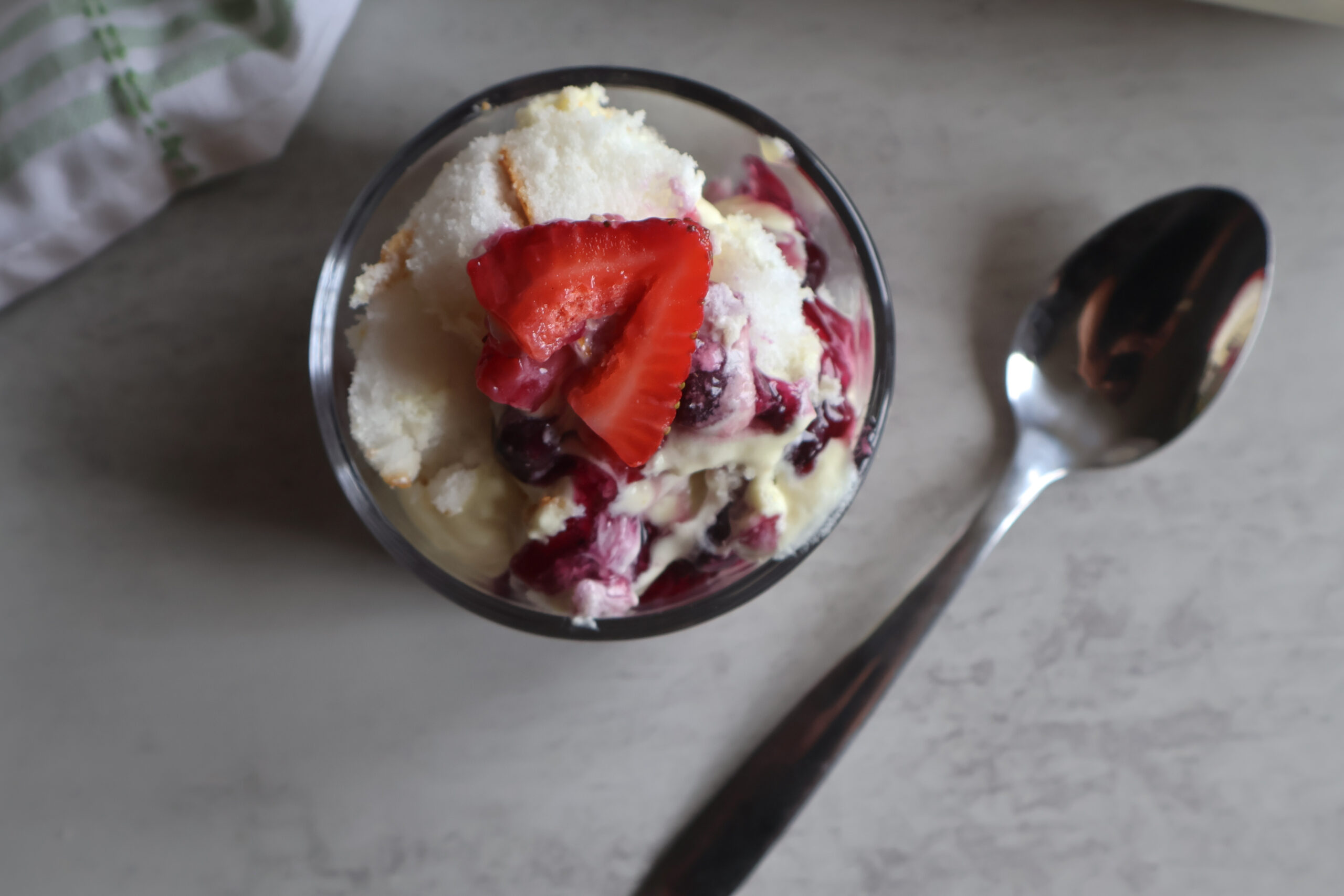 Lemon berry cloud dessert in a small glass dish with a spoon.