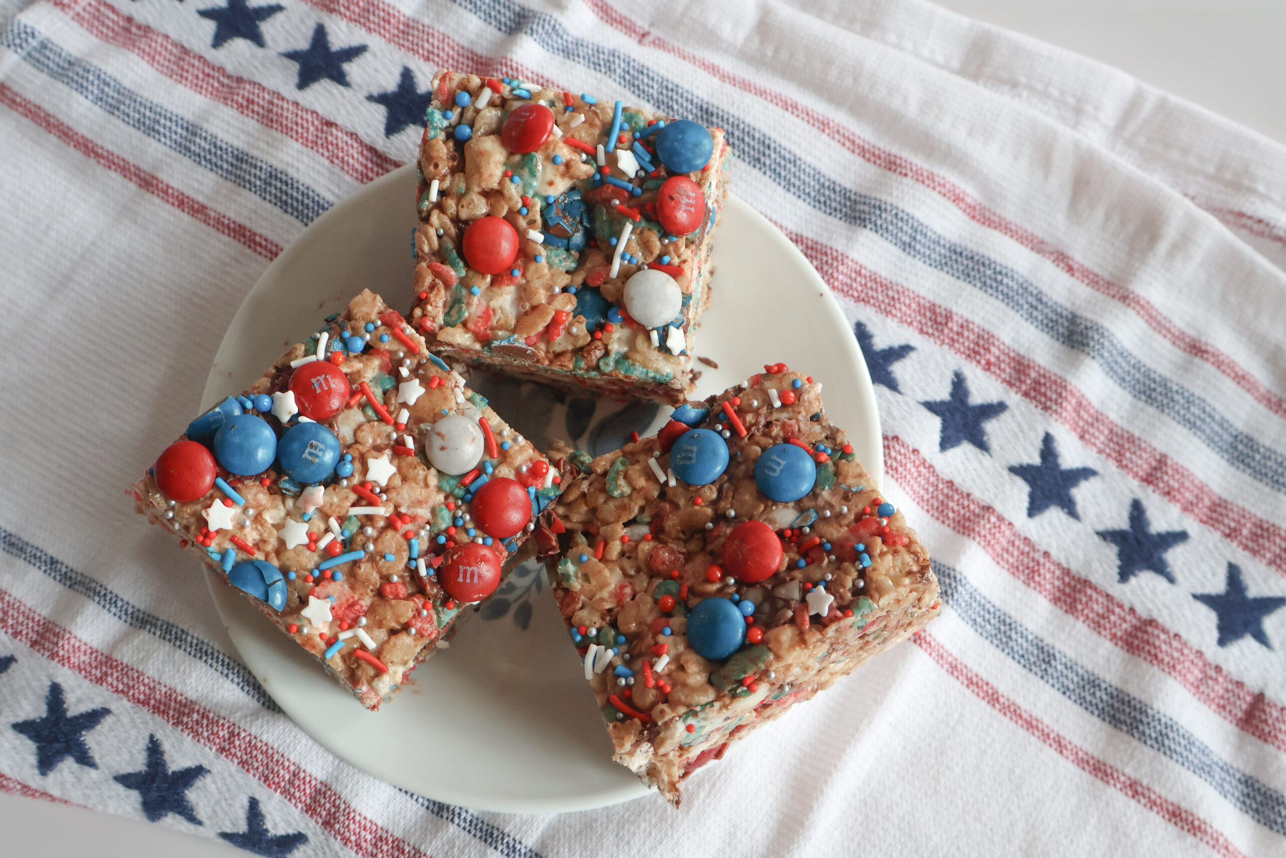 Three browned butter patriotic m&m rice krispie treats on a small plate.