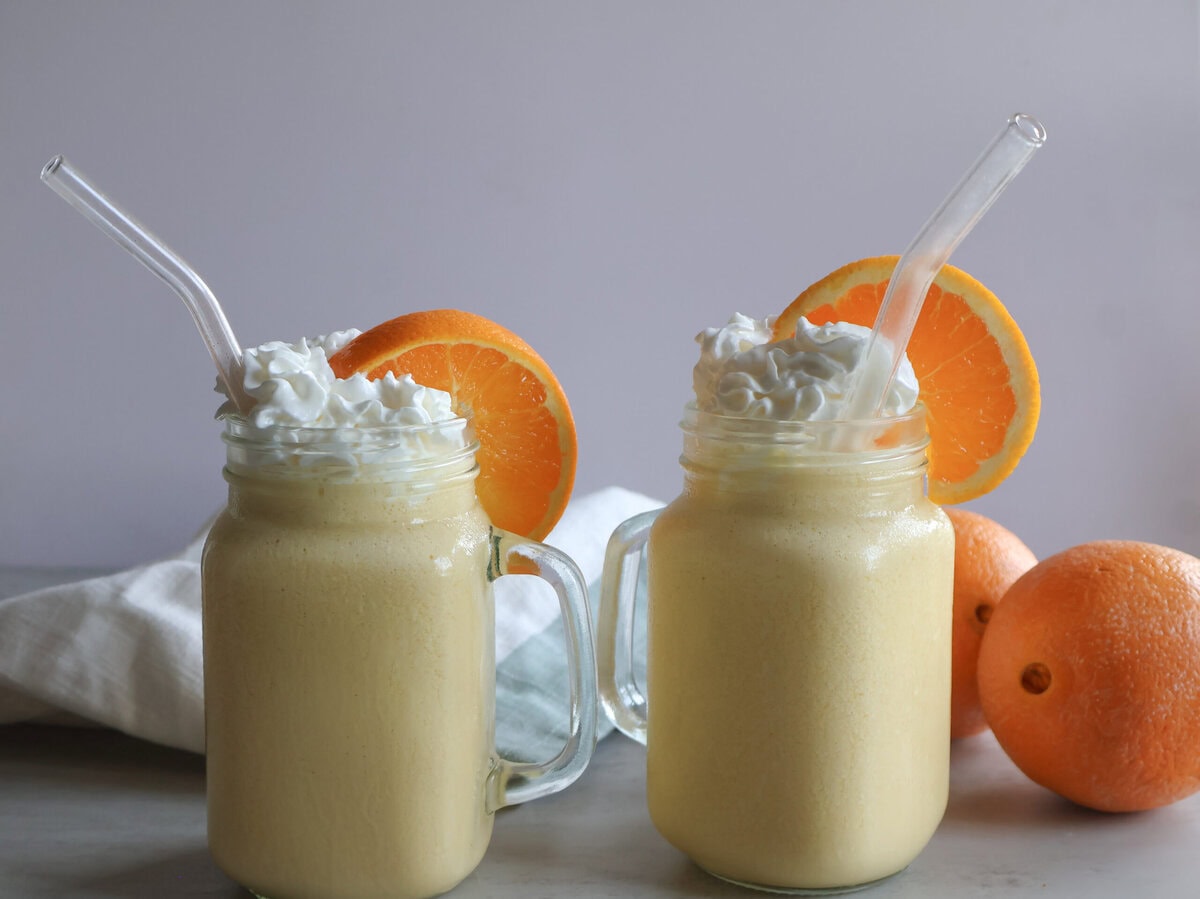 Creamsicle orange frost in a mason jar glass with whipped cream and orange slices.