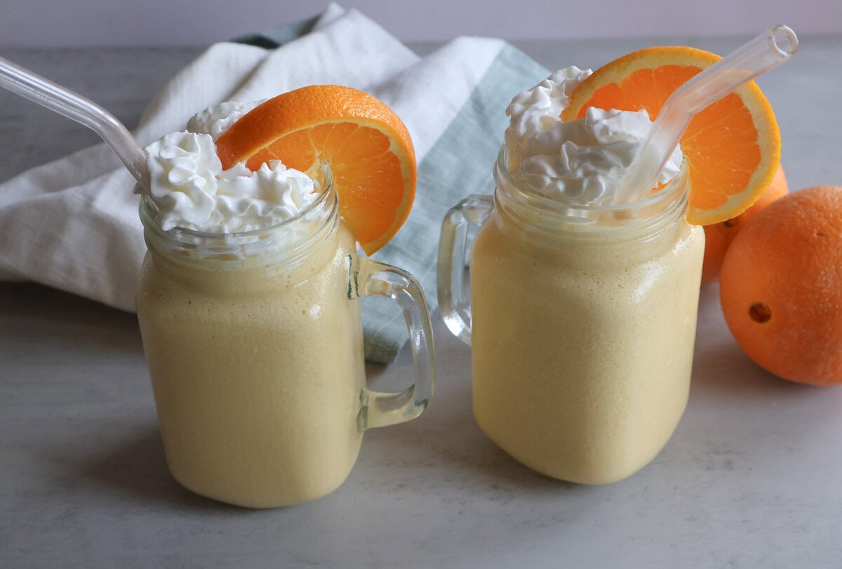 Creamsicle orange frost in glasses with whipped cream and orange slices.