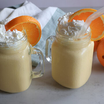 Creamsicle orange frost in mason jar glasses with whipped cream and an orange slice.