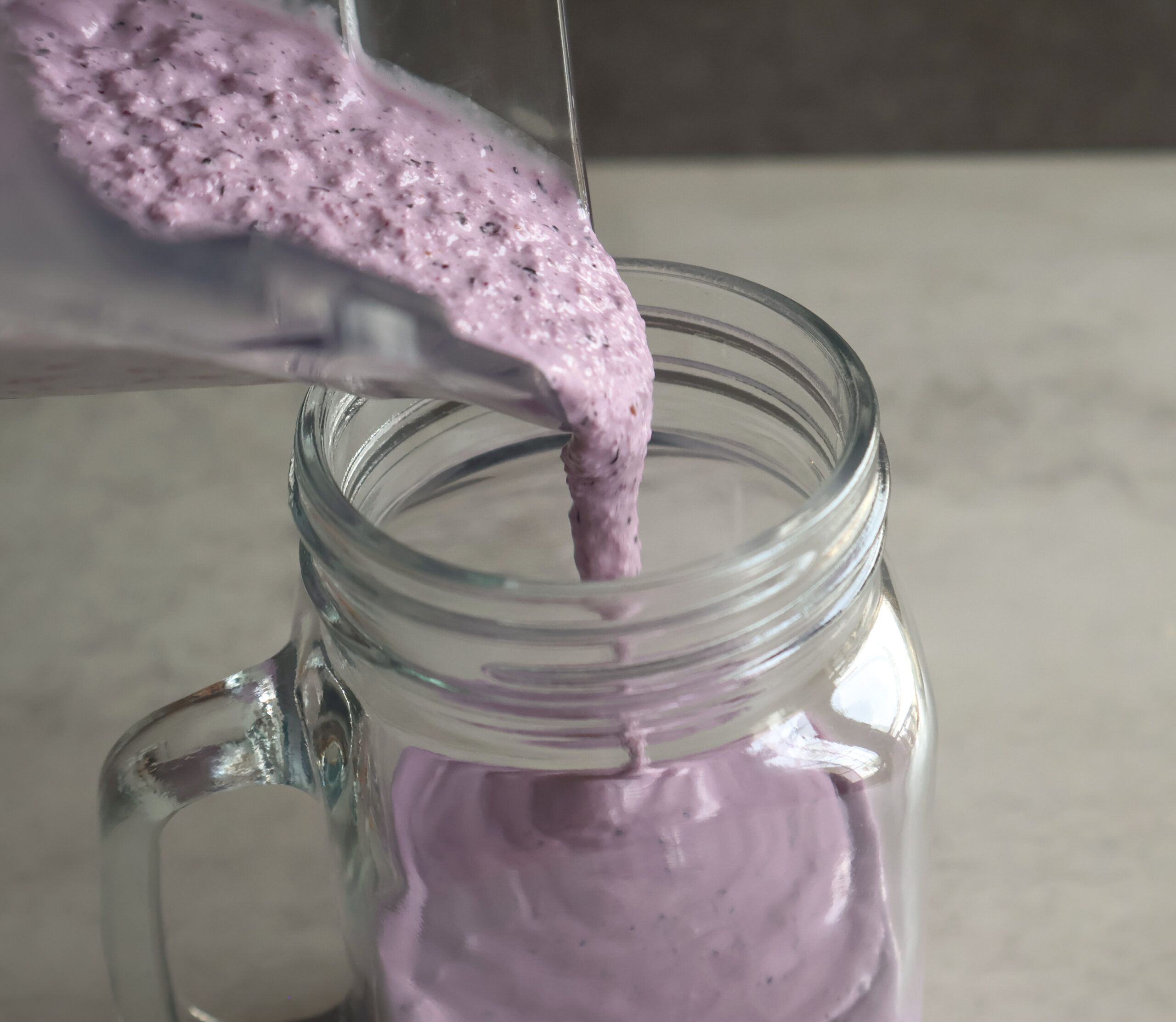 blueberry cheesecake milkshake being poured into a glass.