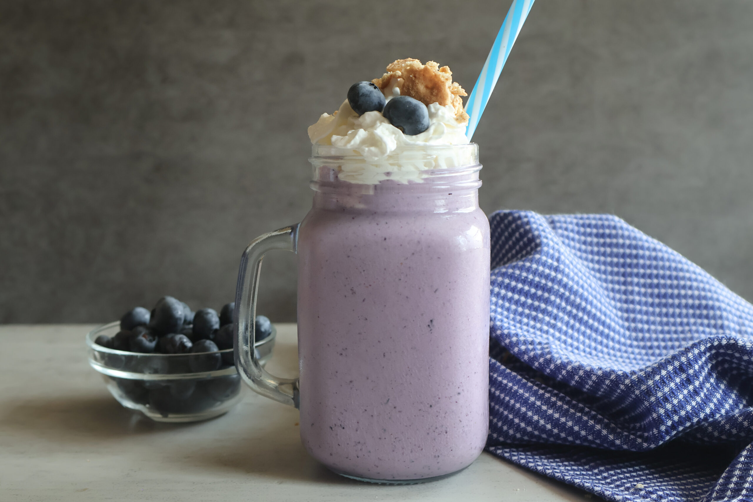 Blueberry cheesecake milkshake with fresh blueberries, graham cracker crumbs, and whipped cream.