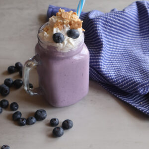 blueberry cheesecake milkshake with fresh blueberries, whipped cream, and crushed graham crackers.